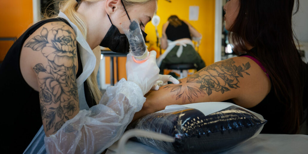 Professionista che tatua su braccio di donna