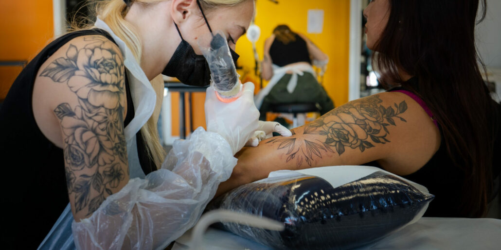 Professionista che tatua su braccio di donna