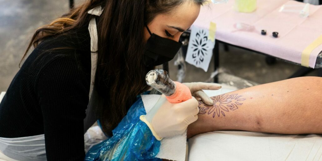 Tatuatrice che esegue tatuaggio ornamentale